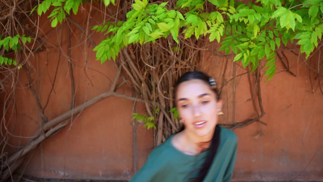 Woman dancing in front of a wall with leaves