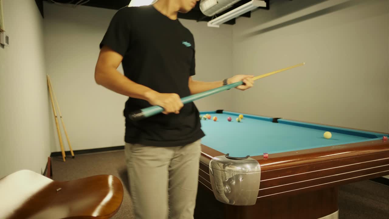 Male co-workers playing pool together on a billiards table in the company recreation room