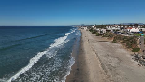 aerial drone shot running parallel along the coastline of carlsbad, california, usa on a bright sunny day