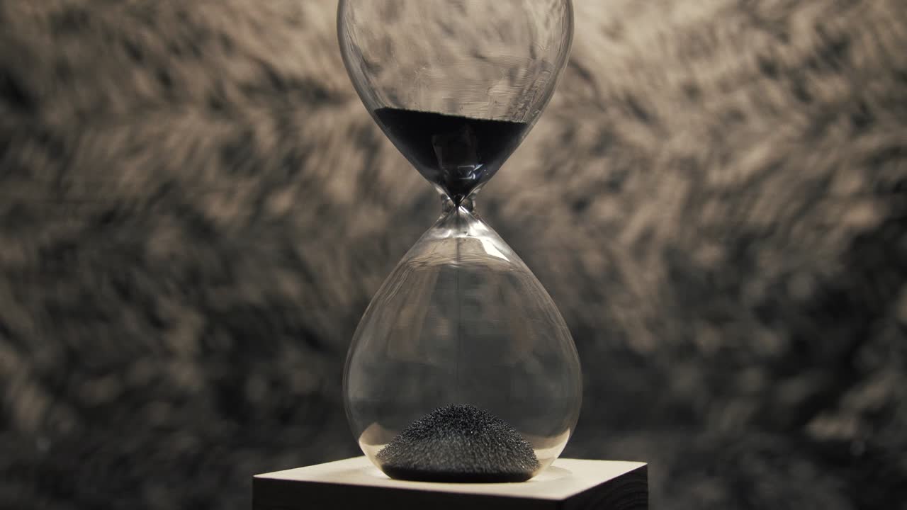 A mesmerizing shot of a magnetic hourglass as iron filings flow down, creating unique patterns