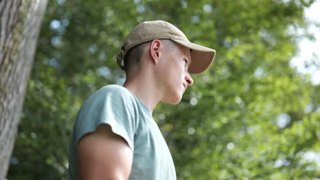 male angler gets fishing rod out surrounded by trees on sunny day, worms perspective