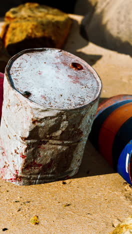 barriles oxidados en una playa de arena