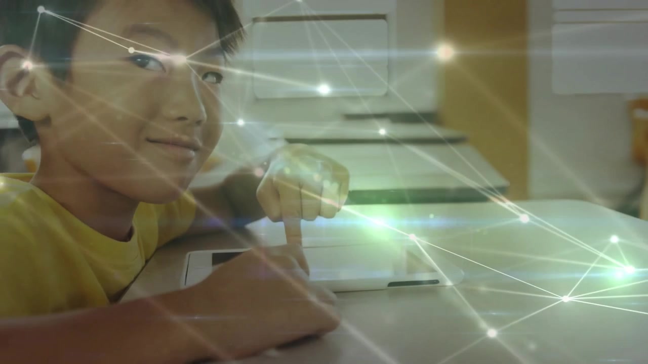 Boy in yellow shirt tapping tablet and summoning animated education icons before smiling at camera