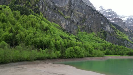 Hermosa-Orilla-Del-Lago-Klontalersee-Con-Montañas-Escarpadas-Y-árboles-Verdes