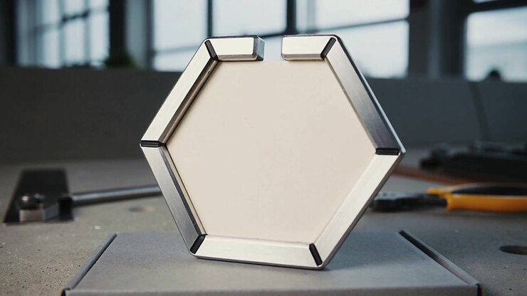 Nudging hexagonal metal puck rocking and rotating on rectangular base, testing balance with pliers