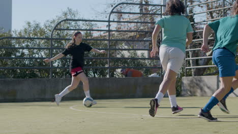 active teenage girls playing football outdoors and one girl scores