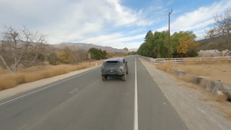 toma aérea de drones fpv del tanque rezvani corriendo en la carretera de montaña