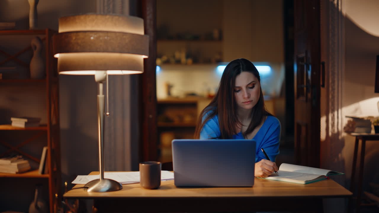 Overloaded manager speaking cellphone reading documents sitting laptop late