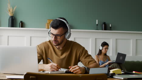 close up view of a student using headphones and opening laptop sitting at table