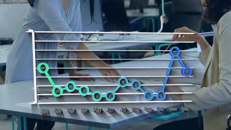 Animation-of-statistical-data-processing-against-two-diverse-women-discussing-over-a-plan-at-office
