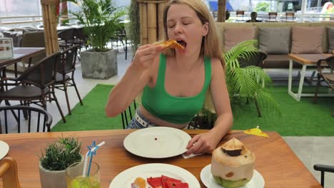 woman eating pizza and coconut water at outdoor restaurant