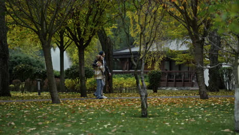 Wide-shot-of-young-walking-couple-going-along-scenic-wood-path-in-early-autumn.