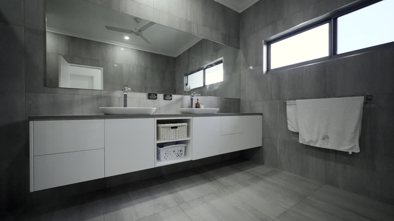 Lujoso baño moderno con elegantes azulejos grises, bañera blanca y grifería blanca en una vivienda residencial contemporánea.