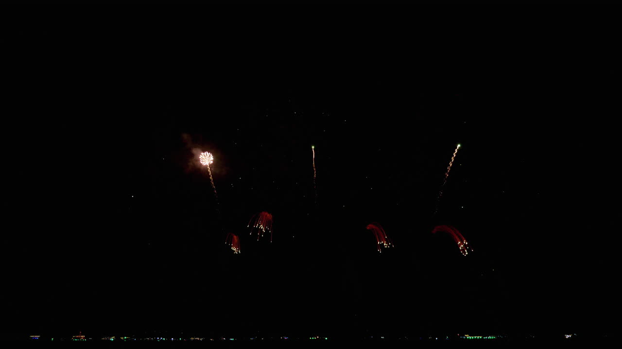 disparando en el cielo nocturno y cayendo hacia atrás en un movimiento sincronizado de luces de colores brillantes durante un festival internacional de fuegos artificiales