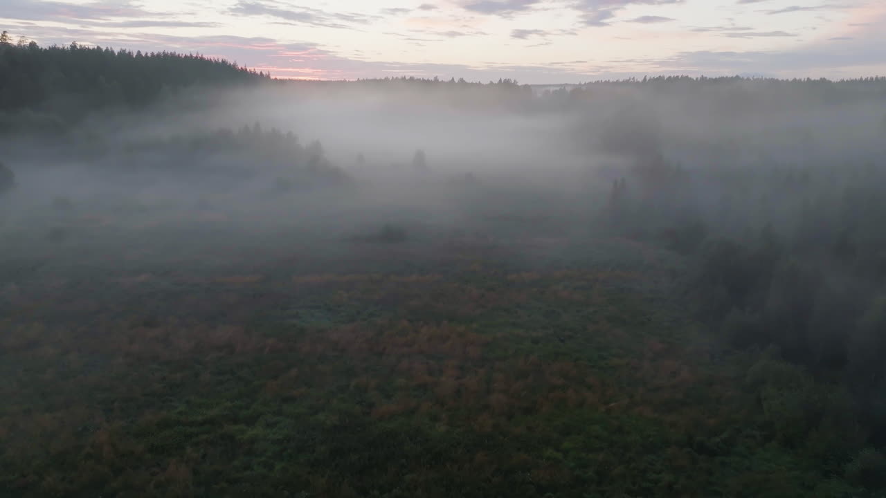 Aerial view over a mist blanketed rural meadow, moody morning in Finland