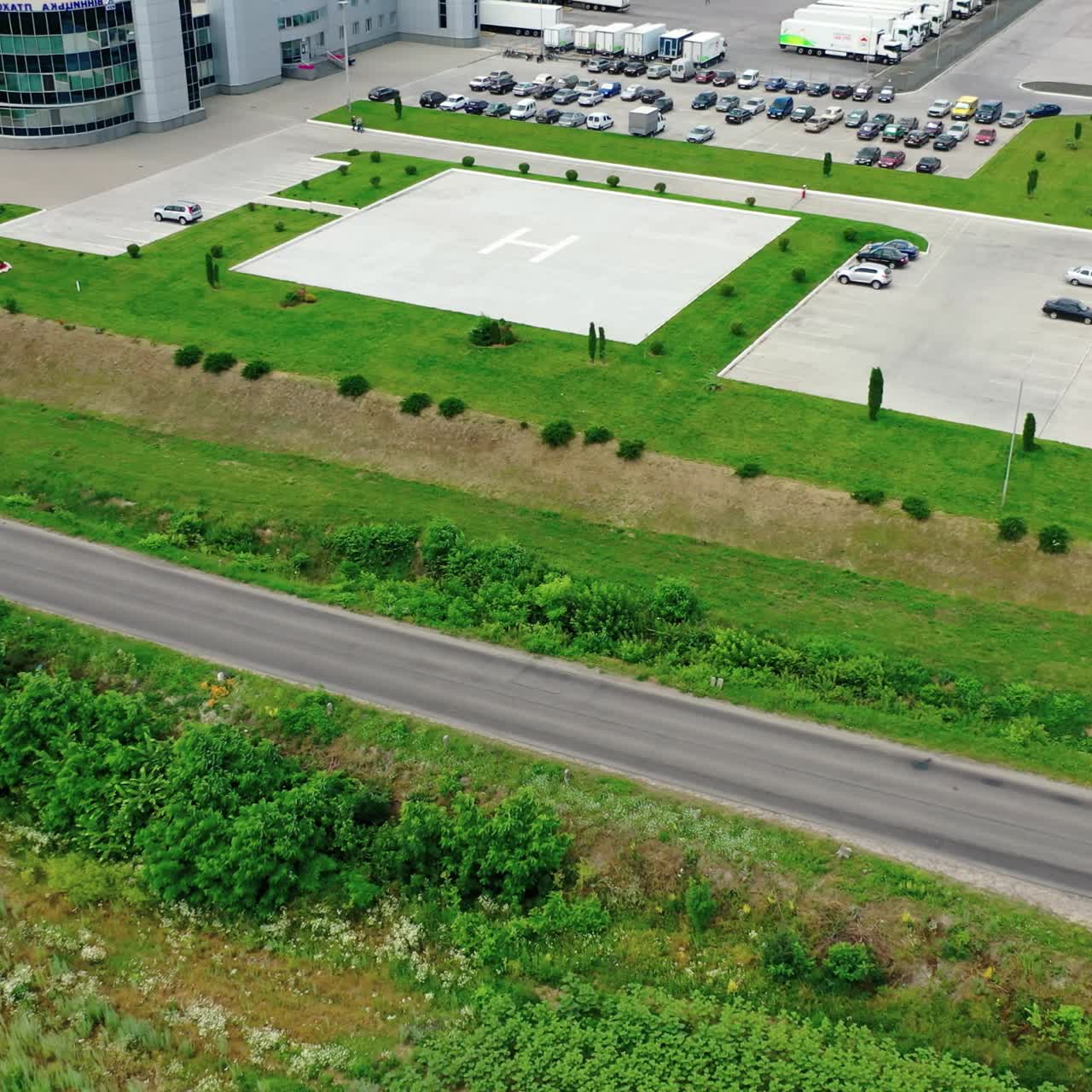 Modern industrial plant on field. Large factory among beautiful green nature. Agricultural center in the countryside. Aerial view