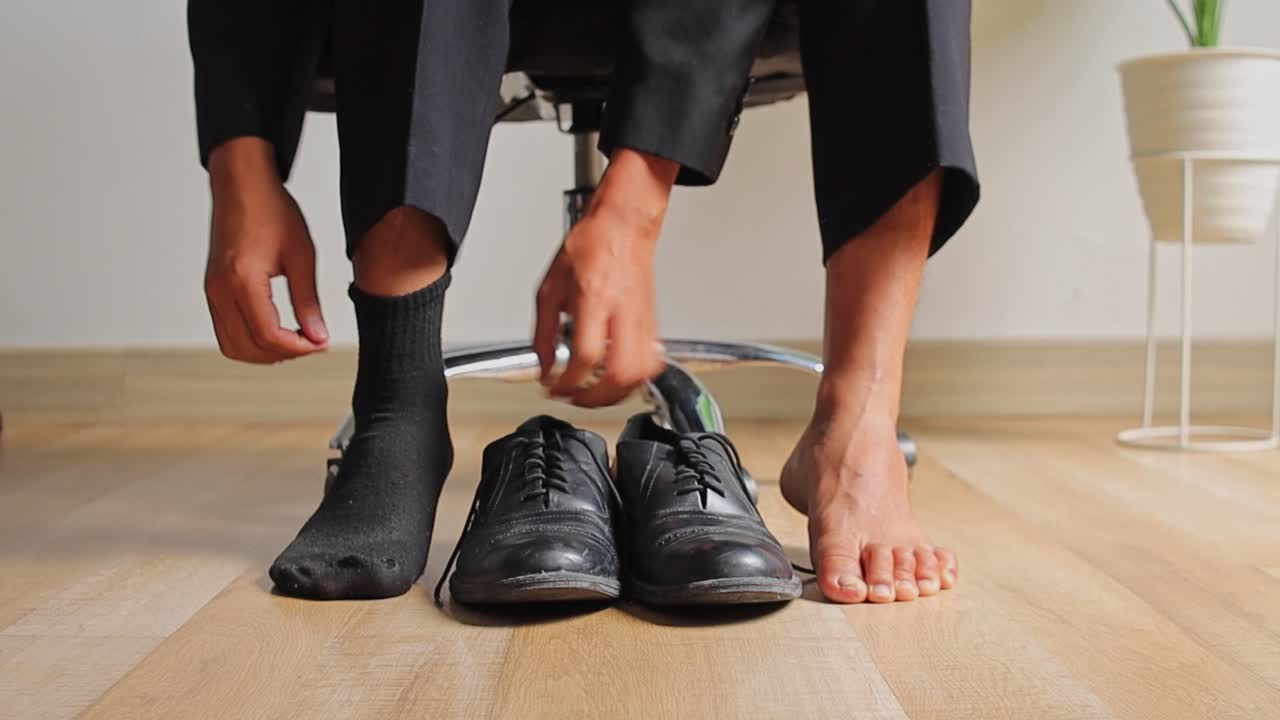 Close-up of businessman in suit sitting in office chair and putting on black dress socks
