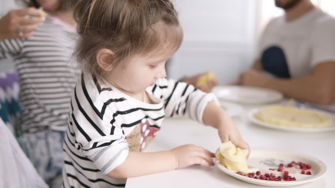 una niña divertida está lamiendo la leche condensada de la tortita mientras la madre alimenta al gato. desayuno familiar