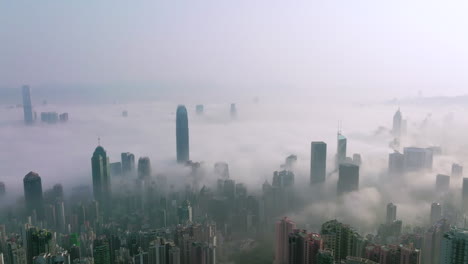 cinematic shot of mystical morning fog covering city of hong kong with high-rise buildings over the clouds