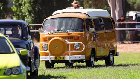 classic orange van driving past parked cars