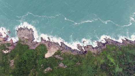 aerial view of a jagged rock island, surrounded with lush green nature and hong kong bay water