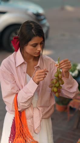 woman buying grapes at a street market