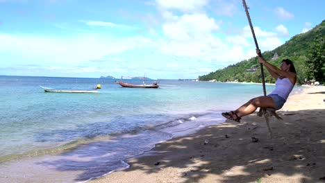 woman swinging on a rope on the beach on the seashore