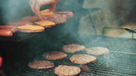 Placing-cheese-slices-on-hamburgers-while-grilling-out-on-a-backyard-barbeque