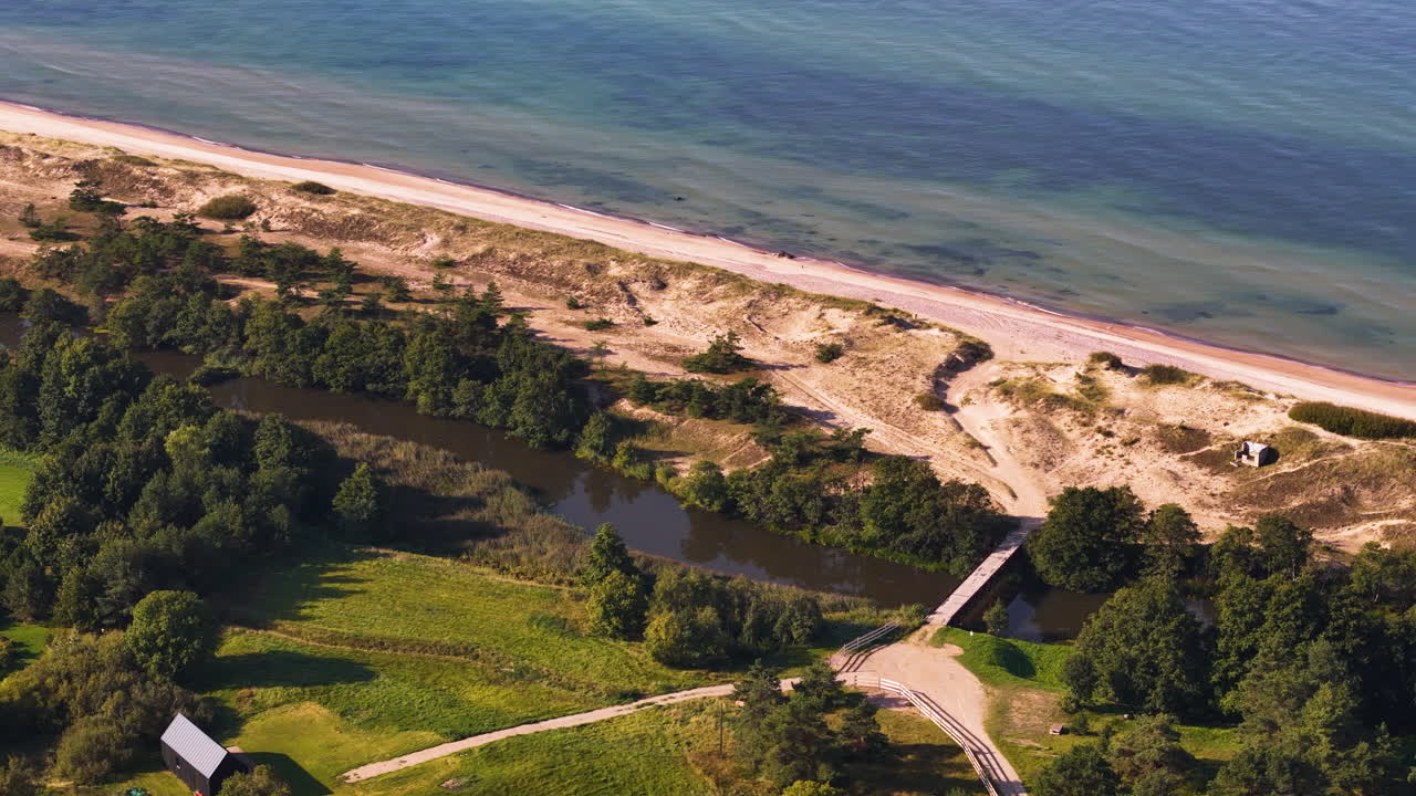 Aerial view of river mouth meeting Baltic Sea with dunes in Uzavas Ieteka Latvia.
