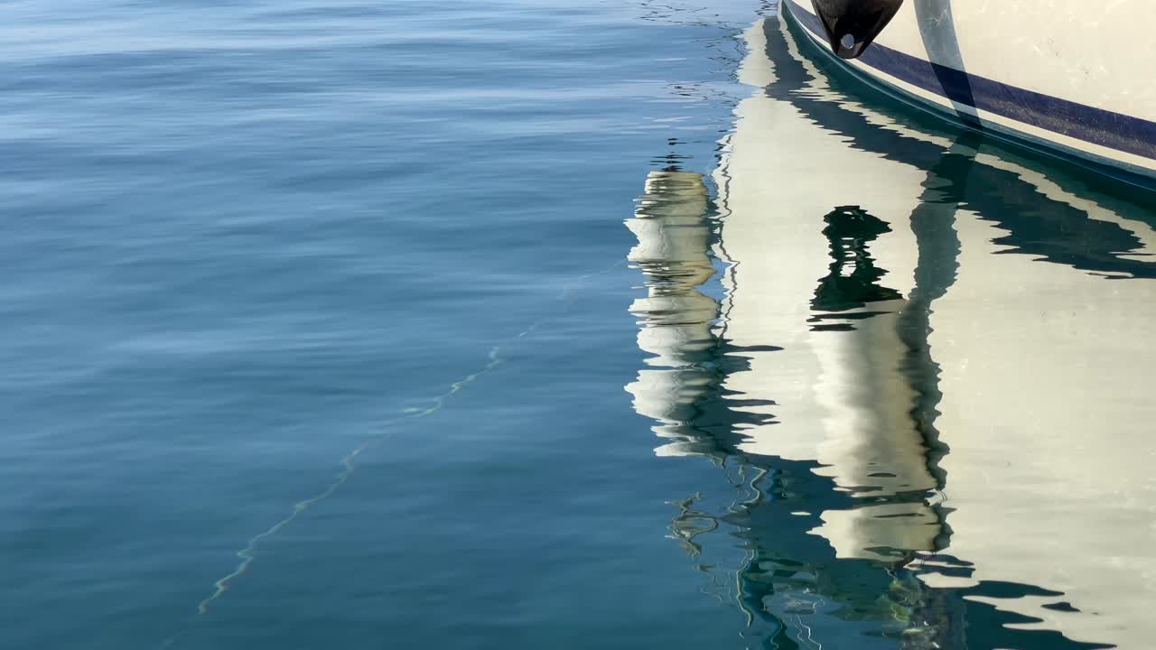 A boat reflects on the clear blue water, creating ripples and a peaceful scene of calm and simplicity.