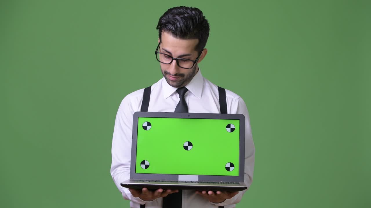 joven empresario persa barbudo y guapo contra un fondo verde