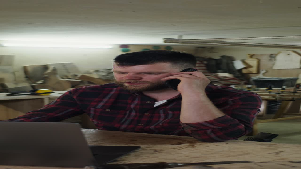 carpintero en una llamada telefónica en el taller