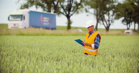 Engineer-Analyzing-Traffic-Polution-On-Clipboard-Amidst-Crops-At-Farm-6