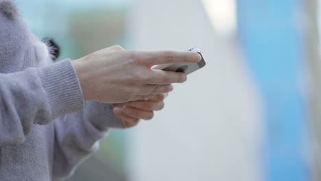 female hands using smartphone on blurred background.