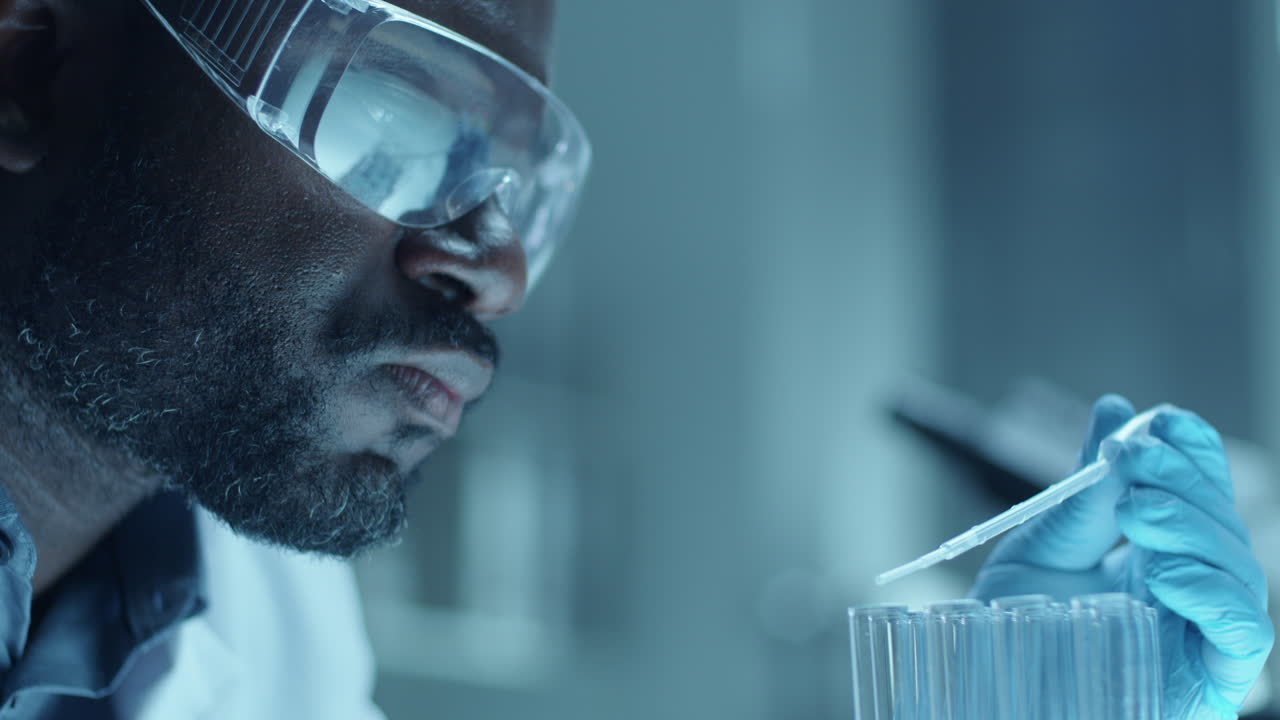 Black Chemist Pouring Liquid in Test Tubes during Laboratory Research