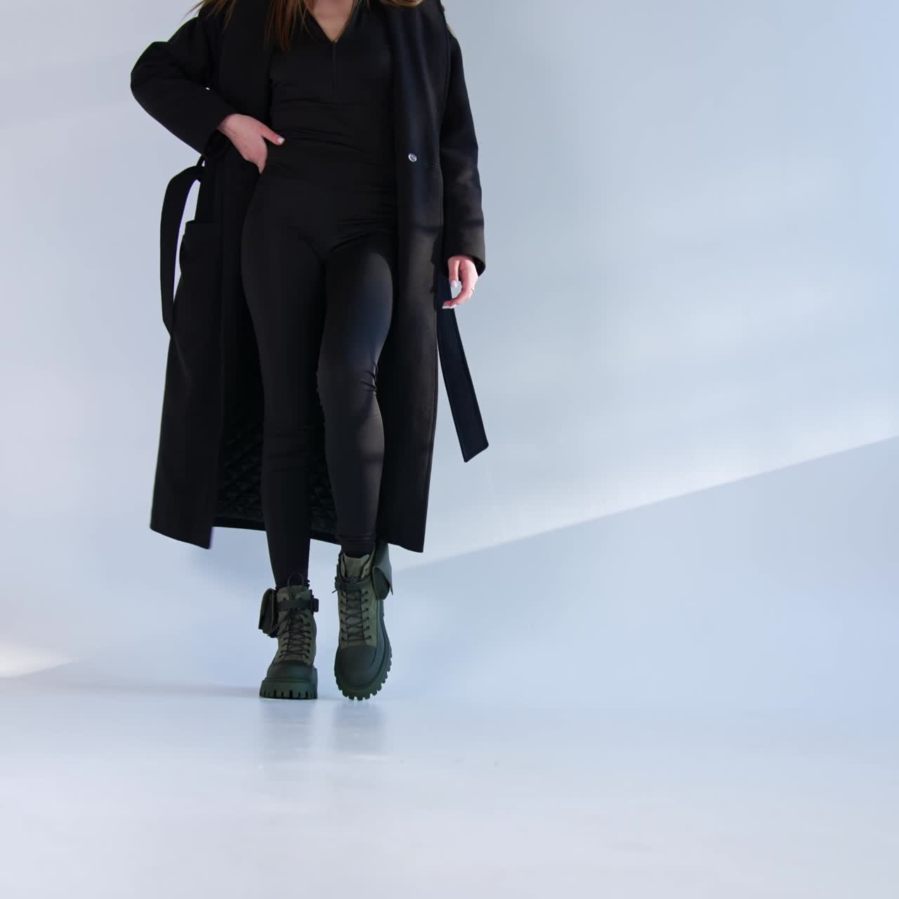 Model in black clothes and stylish boots comes up to the camera. Female demonstrates fashionable combat ankle boots