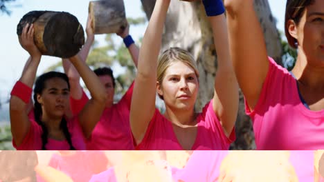 grupo de mujeres haciendo ejercicio con un tronco pesado durante una carrera de obstáculos