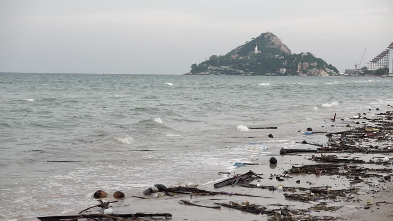 해안을 따라 모래와 물에 있는 플라스틱과 쓰레기 잔해로 가득 찬 매우 오염되고 더러운 해변