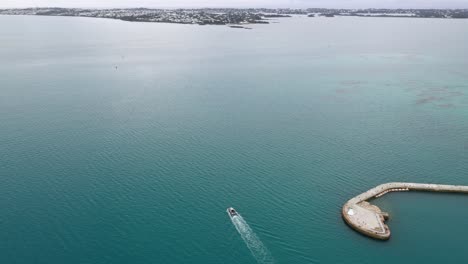 aerial view of boat leaving harbour on tropical island