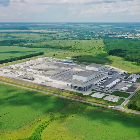 large plant surrounded by green nature. manufacturing in the countryside in summer. modern industrial complex on field. aerial view.
