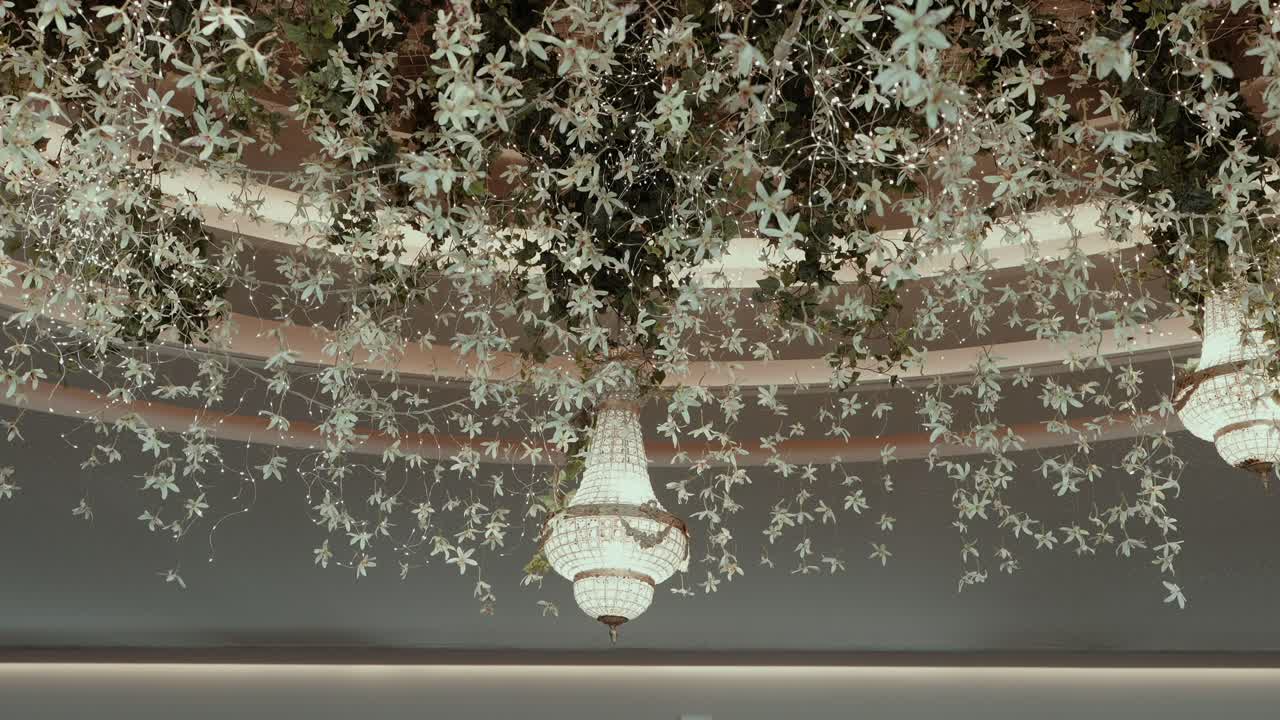 Lujosa lámpara de araña con arreglo floral en cascada para el techo en una recepción de boda