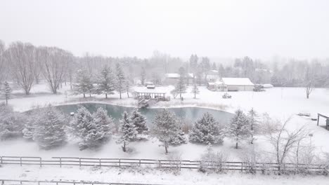 small township with frozen water pond during heavy snowfall, aerial view