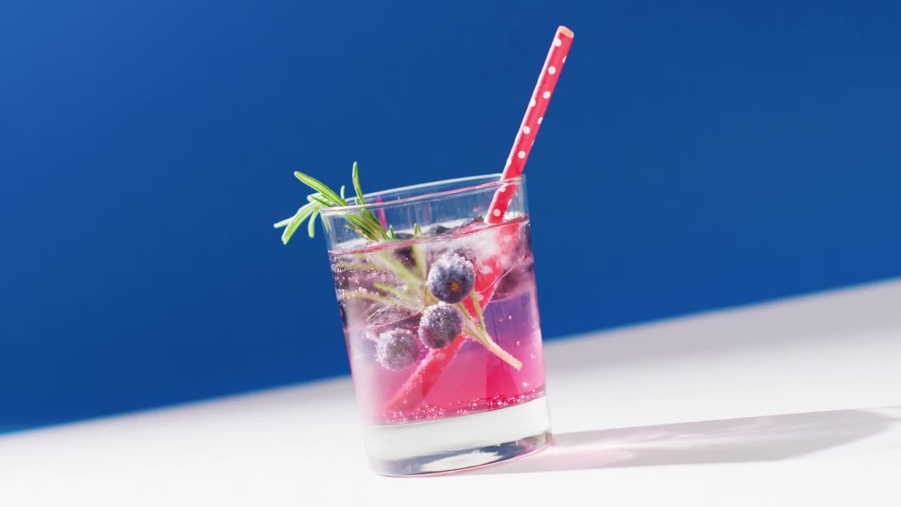 파란색 배경 에 블루베리 가 있는 투명 한 음료 의 클로즈업
