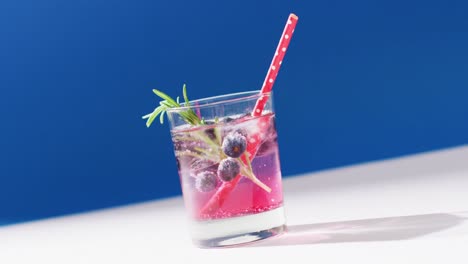 close up of transparent drink with bluberries on blue background