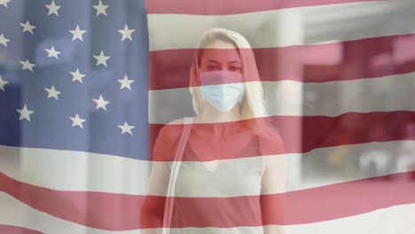 animation of flag of usa waving over caucasian woman wearing face mask in city street