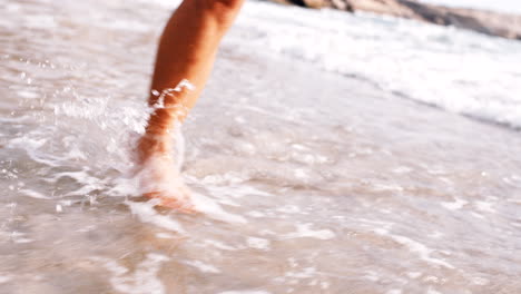 piernas, playa y mujer relajarse con los pies en el agua