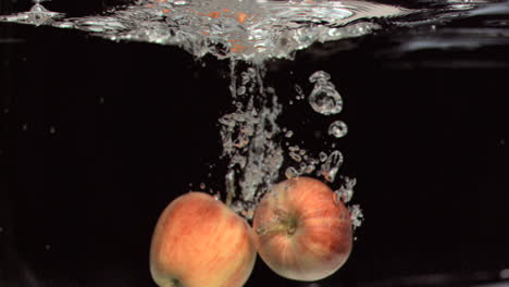 apples falling into water in super slow motion