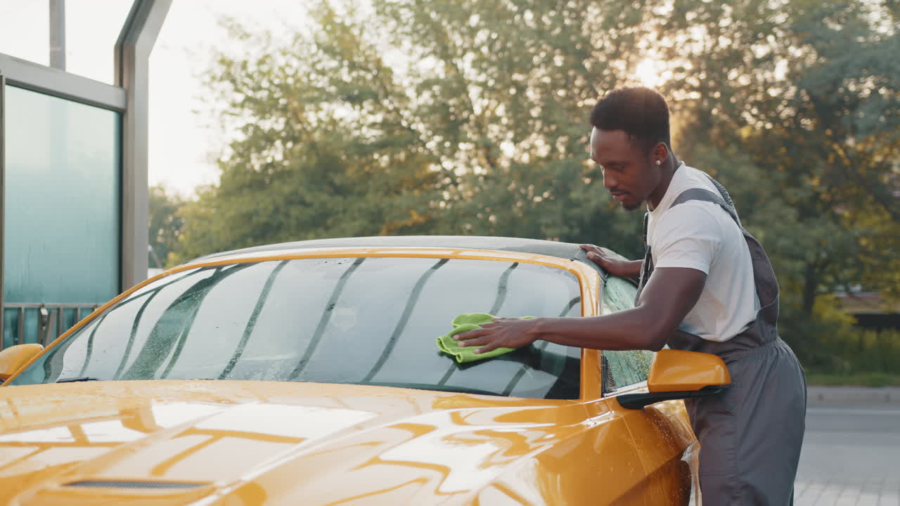 hombre lavando un coche descapotable amarillo