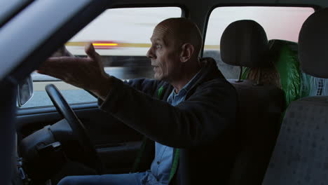 a mature frustrated man with road rage shouting and angry in his car whilst stuck in a traffic jam