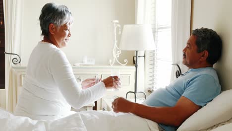 senior woman giving medicine to senior man 4k